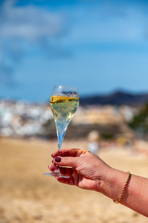 Pouring a glass of champagne on vacation, south of Fuerteventura, Canary islands, blue ocean, mountains, Spainの写真素材