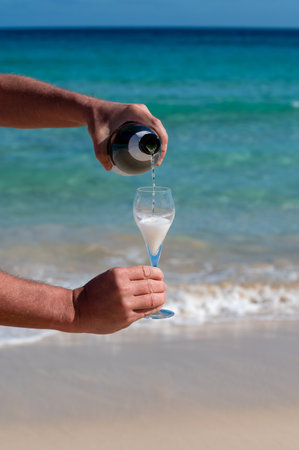 Pouring a glass of champagne on vacation, south of Fuerteventura, Canary islands, blue ocean, mountains, Spainの写真素材