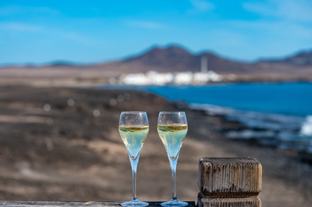 Pouring a glass of champagne on vacation, south of Fuerteventura, Canary islands, blue ocean, mountains, Spainの写真素材