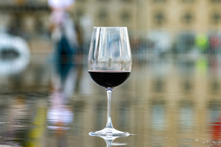 Tasting of Bordeaux blended red wine with wine city Bordeaux on background, left bank of Gironde Estuary, France. Glass of red French wine served outdoor.の写真素材