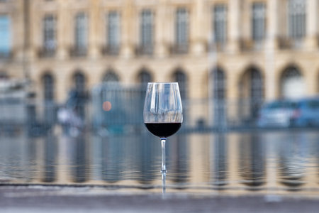 Tasting of Bordeaux blended red wine with wine city Bordeaux on background, left bank of Gironde Estuary, France. Glass of red French wine served outdoor.の写真素材