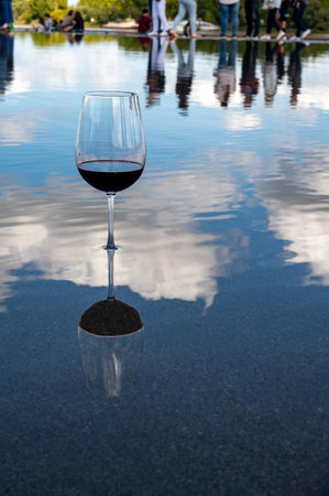 Tasting of Bordeaux blended red wine with wine city Bordeaux on background, left bank of Gironde Estuary, France. Glass of red French wine served outdoor.の写真素材