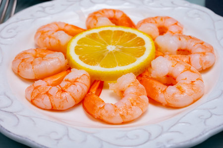 Catch of the day, fresh cooked shrimps served with lemon and garlic sauce on white plate in seafood restaurantの写真素材