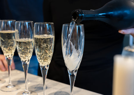 Birthday party, pouring of brut champagne bubbles cava or prosecco wine in tulip glasses with home kitchen on backgroundの写真素材