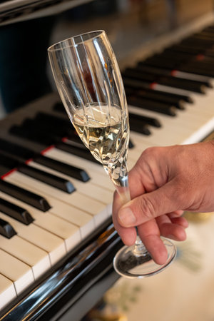 Old grand piano with white ivory keys and glass of champagne sparkling wine close upの写真素材