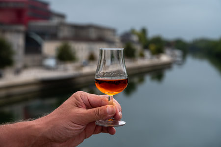 Tasting of aged in barrels cognac alcohol drink and view on old streets and houses in town Cognac, Grand Champagne, Charente, strong spirits distillation industry, Franceの写真素材