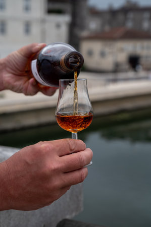 Tasting of aged in barrels cognac alcohol drink and view on old streets and houses in town Cognac, Grand Champagne, Charente, strong spirits distillation industry, Franceの写真素材