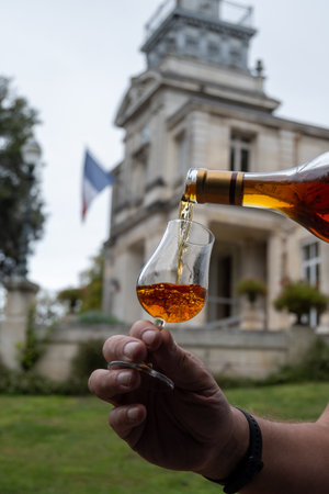 Tasting of aged in barrels cognac alcohol drink and view on old streets and houses in town Cognac, Grand Champagne, Charente, strong spirits distillation industry, Franceの写真素材