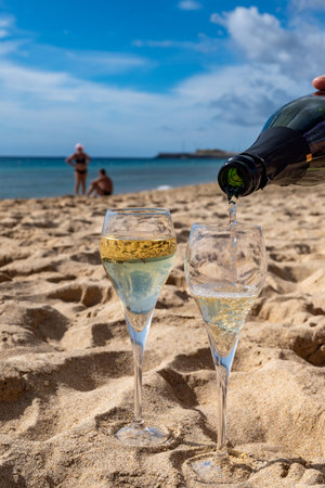 Pouring a glass of champagne on vacation, south of Fuerteventura, Canary islands, blue ocean, mountains, Spainの写真素材