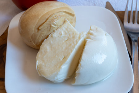 Tasty Italian food, small balls of smoked and white mozzarella soft cheese served on white boardの写真素材