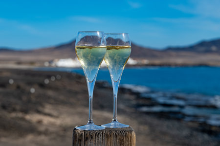 Pouring a glass of champagne on vacation, south of Fuerteventura, Canary islands, blue ocean, mountains, Spainの写真素材