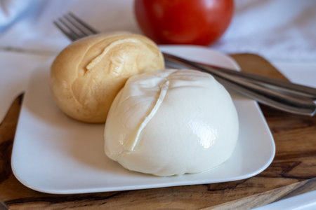 Tasty Italian food, small balls of smoked and white mozzarella soft cheese served on white boardの写真素材