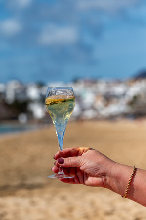 Pouring a glass of champagne on vacation, south of Fuerteventura, Canary islands, blue ocean, mountains, Spainの写真素材