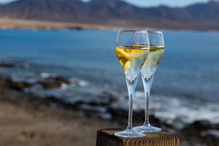 Pouring a glass of champagne on vacation, south of Fuerteventura, Canary islands, blue ocean, mountains, Spainの写真素材