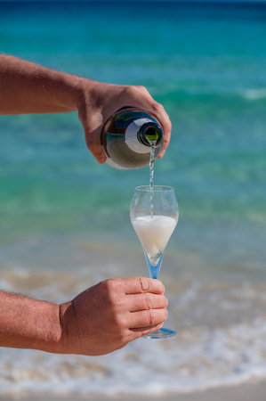 Pouring a glass of champagne on vacation, south of Fuerteventura, Canary islands, blue ocean, mountains, Spainの写真素材