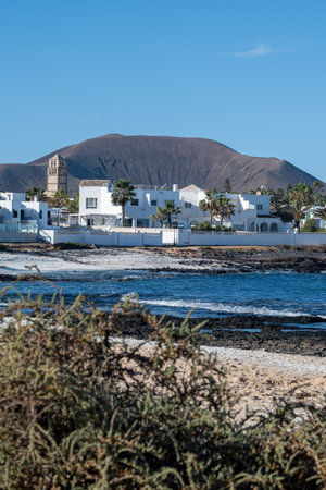 Walking on sea promenade in Corralejo town along white popcorn beach with white corals, black rocks, blue water, Fuerteventura, Canary islands, Spainの写真素材
