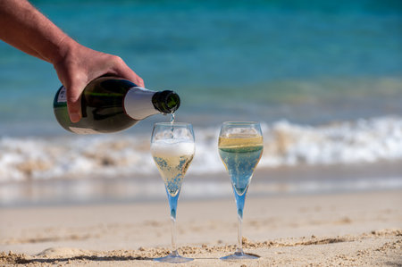 Pouring a glass of champagne on vacation, south of Fuerteventura, Canary islands, blue ocean, mountains, Spainの写真素材