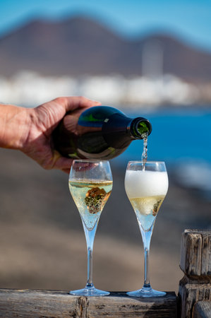 Pouring a glass of champagne on vacation, south of Fuerteventura, Canary islands, blue ocean, mountains, Spainの写真素材