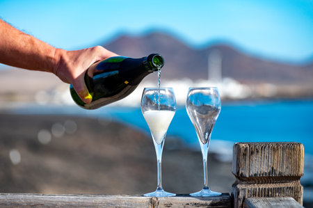 Pouring a glass of champagne on vacation, south of Fuerteventura, Canary islands, blue ocean, mountains, Spainの写真素材