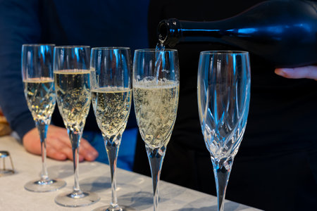 Birthday party, pouring of brut champagne bubbles cava or prosecco wine in tulip glasses with home kitchen on backgroundの写真素材