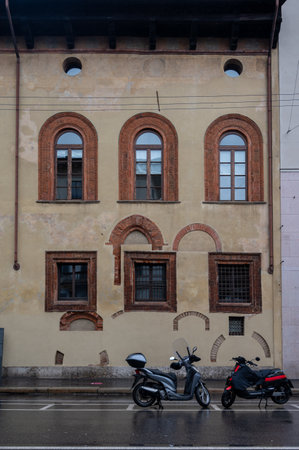 Old house with medieval windows and motor bike on rainy day in Milan, Italyの写真素材