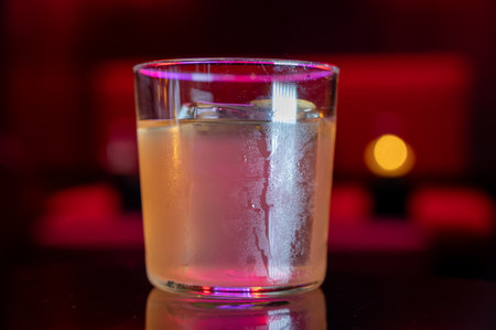 Whiskey and rum colorful cocktails served with ice cubes on black table in dark cocktail night bar...