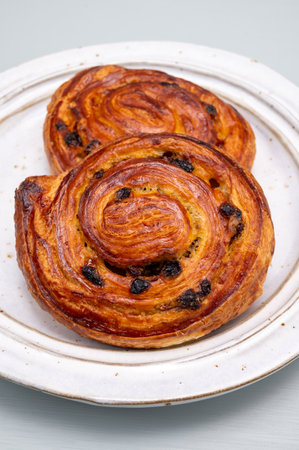 Breakfast in bakery with freshly baked two coffee buns sweet pastry with raisins, morning food close upの写真素材