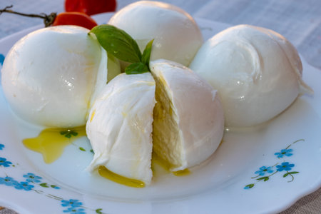 Cheese collection, white balls of soft Italian cheese mozzarella, served with olive oil, tomatoes, fresh basil leaves close upの写真素材