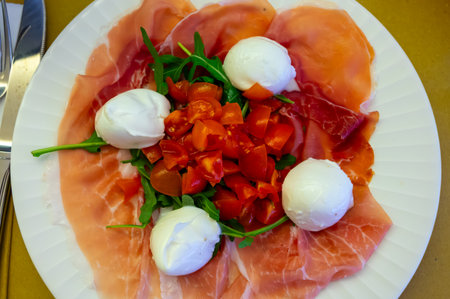 Cuisine of Emilia-Romagna region, Caprese salad with Prosciutto crudo, prosciutto di Parma, mozzarella and tomatoes, lunch in Parma, Italyの写真素材