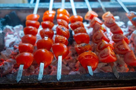 Barbecue with ripe red tomatoes on flamed charcoal grill in turkish restaurantの写真素材