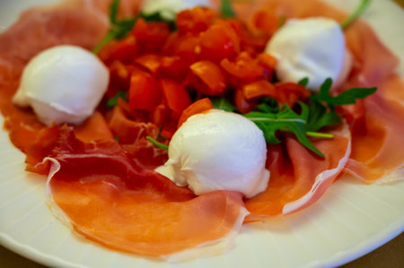 Cuisine of Emilia-Romagna region, Caprese salad with Prosciutto crudo, prosciutto di Parma, mozzarella and tomatoes, lunch in Parma, Italyの写真素材