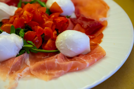 Cuisine of Emilia-Romagna region, Caprese salad with Prosciutto crudo, prosciutto di Parma, mozzarella and tomatoes, lunch in Parma, Italyの写真素材