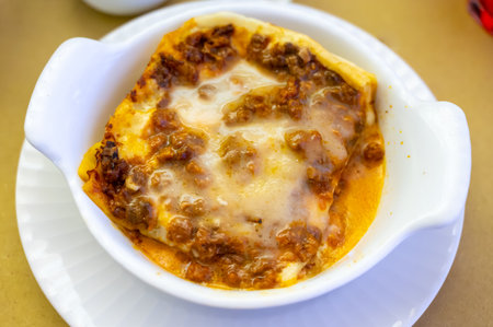 Traditional first course for lunch or dinner in Italy, lasagna Bolognese with beef meat and bechamel sauce served in Italian restaurant, Milan, Italy, close upの写真素材
