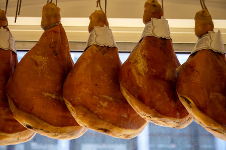 Prosciutto crudo, prosciutto di Parma, uncooked, unsmoked, and dry-cured ham from Parma, Emilia-Romagna, Italy, pork legs hanging in restaurantの写真素材
