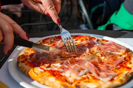 Eating of fresh baked pizza dish in italian pizzeria restaurant with cheese and Prosciutto di Parmaの写真素材