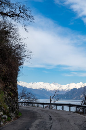 Driving car on road along shores of Lake Como in Northern Italy, spring sunny days, views of alpine mountains, water and villagesの写真素材