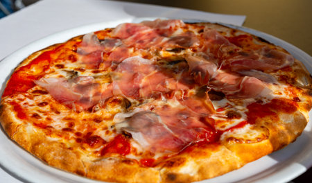 Eating of fresh baked pizza dish in italian pizzeria restaurant with cheese and Prosciutto di Parmaの写真素材