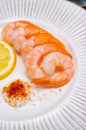 Catch of the day, fresh cooked shrimps served with lemon and garlic sauce on white plate in seafood restaurantの写真素材
