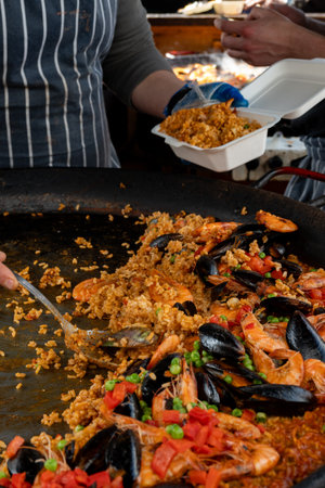 Street food in London, food court on Portobello road Saturday market, freshly prepared colorful paella with rice and sea food in big pan, ready to eatの写真素材