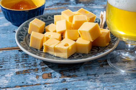 Cheese collection, Dutch ripe hard cheeses made from cow milk in the Netherlands in cubes and glass of white beerの写真素材