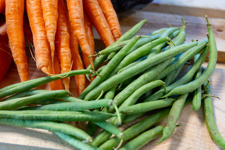 Bunch on fresh orange carrots and green beans on wooden box close upの写真素材