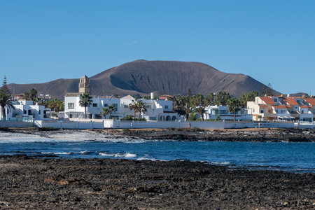 Walking on sea promenade in Corralejo town along white popcorn beach with white corals, black rocks, blue water, Fuerteventura, Canary islands, Spainの写真素材