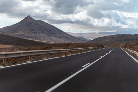 Mountain asphalt road on colorful remote basal hills and mountains of Massif of Betancuria, Fuerteventura, Canary islands, Spain, travel destinationの写真素材