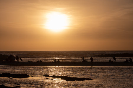 Man and woman staying and looking at sunset on ocean beach, orange sky, silhouettes of people on vacation, Canary islandsの写真素材