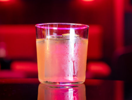 Whiskey and rum colorful cocktails served with ice cubes on black table in dark cocktail night bar in Italyの写真素材