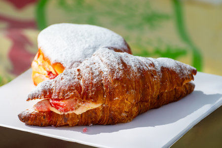 Dutch cuisine, fresh baked strawberry cake and croissant with cream and fresh fruits served in outdoor cafeの写真素材