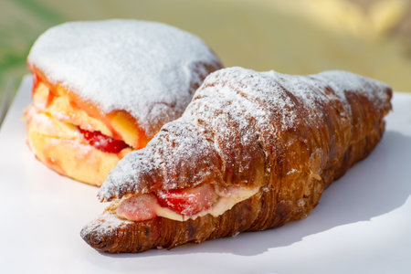 Dutch cuisine, fresh baked strawberry cake and croissant with cream and fresh fruits served in outdoor cafeの写真素材