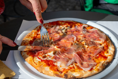 Eating of fresh baked pizza dish in italian pizzeria restaurant with cheese and Prosciutto di Parmaの写真素材