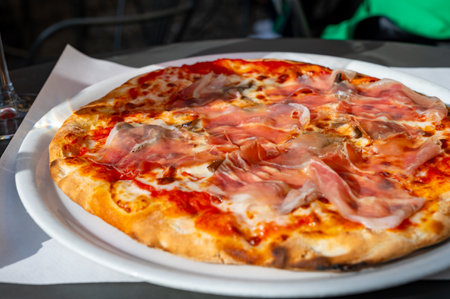 Eating of fresh baked pizza dish in italian pizzeria restaurant with cheese and Prosciutto di Parmaの写真素材