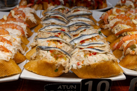 Typical snacks of Basque Country, variety of pinchos or pinxtos oven baked sea food, bread, anchovy, shrimps salad, cheese served in bars in San-Sebastian or Bilbao, Spainの写真素材